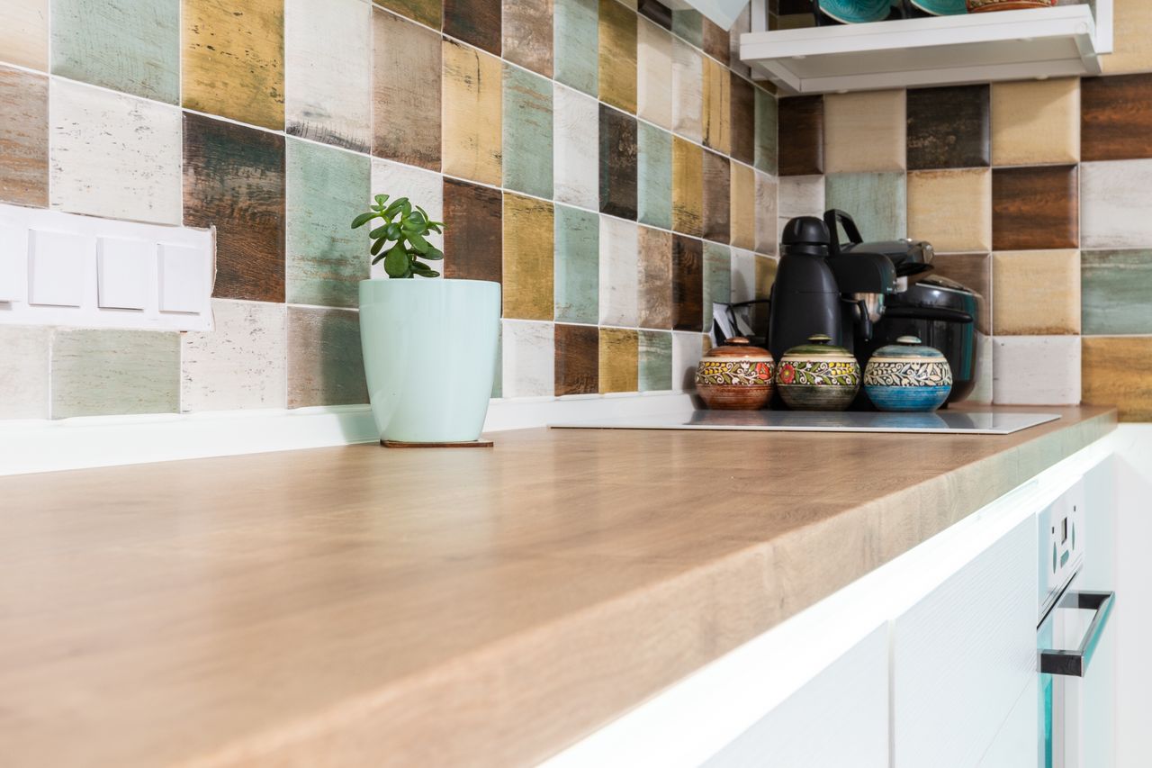 Home Interior of light kitchen furnished with wooden counter with multicolored tiled backsplash and various dishware
